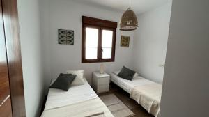 dwa łóżka w pokoju z oknem w obiekcie Casa adosada panorámica al mar w Almuñécar +11 zdjęć