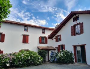 a white house with red windows and flowers at Maison Irriberria in Hasparren