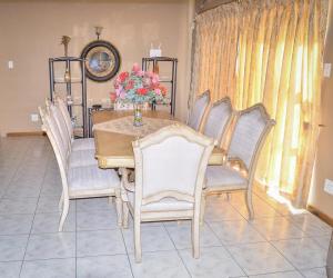 a dining room table with chairs and a vase of flowers at Mountain Beauty in Mbabane