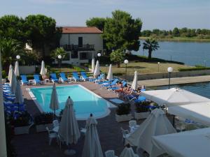 Cassano Jonio的住宿－Hotel Oleandro，一座带椅子和遮阳伞的游泳池位于一座建筑旁边