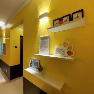 um quarto com uma parede amarela com prateleiras e um computador portátil em Comfy Stay @Permai Puteri Ampang nearby KLCC, IJN em Ampang