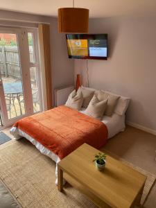 ein Schlafzimmer mit einem Bett mit einer orangefarbenen Decke in der Unterkunft Coventry City Centre townhouse with private parking in Coventry