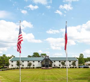 two flags on poles in front of a building at Carolina Pine Inn near Southern Pines-Pinehurst in Pinebluff