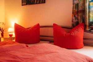 zwei rote Kissen auf dem Bett in der Unterkunft Ferienwohnung LePetit in Steina