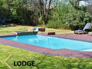 a pool in a yard with a bench next to it at Korundum Lodge in Vereeniging