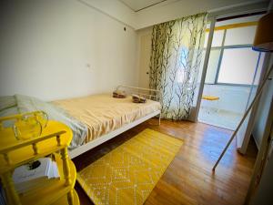 - une chambre avec un lit, une fenêtre et un tabouret jaune dans l'établissement Lovely 50 sq penthouse & 25 sq balcony @ Glyfada, à Athènes