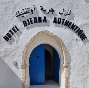 un bâtiment avec une porte bleue et un panneau sur celui-ci dans l'établissement Hôtel Djerba Authentique - Au centre de Midoun, à Midoun