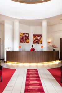 a man standing at a reception desk in a hotel lobby at Hôtel Savoie Léman in Thonon-les-Bains
