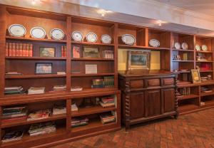 ナチェズにあるThe Burn Bed and Breakfastの木製の棚と皿、本が並ぶ図書室