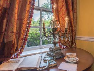a table with a book and a lamp and a window at The Burn Bed and Breakfast in Natchez