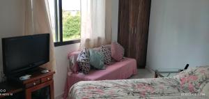 a bedroom with a bed and a tv and a window at Studio Canto Forte - Praia Grande in Praia Grande