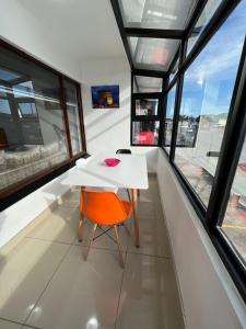una mesa blanca y una silla naranja en una habitación con ventanas en Safi Luxury Apartment 7, en East London