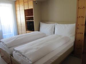 ein großes weißes Bett mit weißer Bettwäsche und Kissen in der Unterkunft Studio im Hotel Des Alpes in Flims