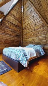 a bed in a thatched room with a keyboard at Alas Glamping La Cima in Guatavita