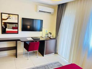 a room with a desk with a television and a bed at Souaré Premium Hôtel in Conakry