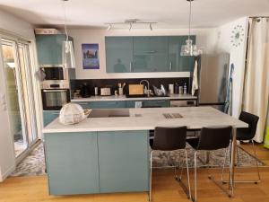 a kitchen with blue cabinets and a counter with chairs at La Balancelle in Marseille