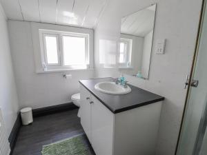 a white bathroom with a sink and a mirror at The Bookcase in Colwyn Bay