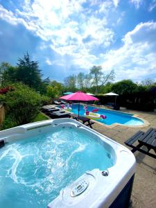a jacuzzi tub with an umbrella next to a pool at The Farm Exclusive Hire in Stapleford Tawney