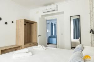 1 dormitorio con cama blanca y espejo en La Luz de la Viña - FREE PARKING by Cadiz Time, en Cádiz