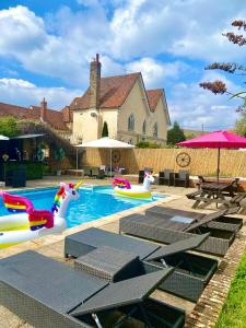 a pool with inflatables and tables and a house at The Farm Exclusive Hire in Stapleford Tawney