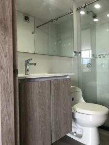 a bathroom with a toilet and a sink and a mirror at Espectacular apartamento con estacionamiento gratuito Chía N 2 in Chía