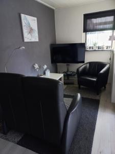 a living room with black furniture and a flat screen tv at Appartement Ons Plekje in De Wilp