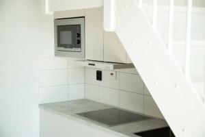 a white kitchen with a microwave and a stove at SK67 Stylish and Full Equipped loft with free parking in Lidingö