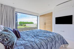 een slaapkamer met een groot bed en een groot raam bij Seafire Beach House - West Wittering in West Wittering