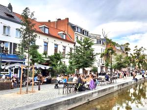 eine Gruppe von Menschen, die an Tischen neben einem Fluss sitzen in der Unterkunft St Catherine - Sweet home - Bxl - Studio Apartment with city view in Brüssel