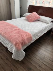 una coperta e cuscini rosa di peluche su un letto di Espectacular apartamento con estacionamiento gratuito Chía N 2 a Chía