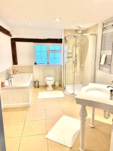 a bathroom with a tub and a sink and a shower at The Farm Exclusive Hire in Stapleford Tawney