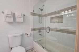 uma casa de banho branca com um chuveiro e um WC. em 5 BR Mansion with Pool and non-heated Jacuzzi Games in Boynton Beach em Boynton Beach