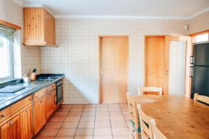 uma cozinha com armários de madeira e uma mesa de madeira em Just Like Home - Casa do Sobreiro Velho em Cerveira em Vila Nova de Cerveira