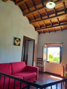 un soggiorno con divano rosso e finestra di Domus de Jara - Casa Montis a Baradili