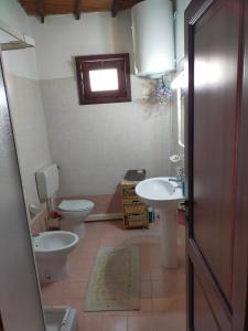 baño con 2 aseos, lavamanos y ventana en Domus de Jara - Casa Montis en Baradili