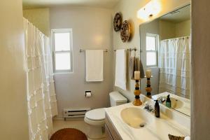 ein Badezimmer mit einem Waschbecken, einem WC und einem Spiegel in der Unterkunft Vintage charm vacation home with modern comforts near Old Town in Albuquerque