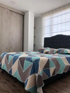 una camera con un letto con una trapunta sopra di Espectacular apartamento con estacionamiento gratuito Chía N 2 a Chía