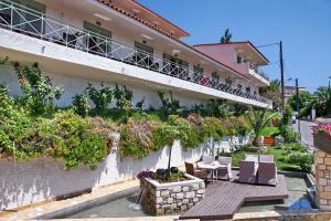 un edificio con balcone arredato con sedie e tavolo di Sandy Bay Hotel a Plomari