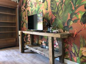 - un salon avec une télévision sur un mur fleuri dans l'établissement Jardin des Pérelles, à Varengeville-sur-Mer