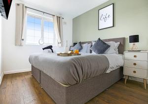a bedroom with a large bed and a window at Walnut House - Close to City Centre - Free Parking, Fast Wifi and Smart TVs by Yoko Property in Milton Keynes