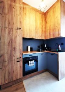 a kitchen with wooden cabinets and a black oven at PODWALE Apartment - Self Check-In 24h in Wrocław