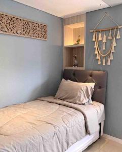 1 cama en un dormitorio con una pared azul en Daymentroom R32 Apartemen 2 BR Pasteur Bandung, en Bandung