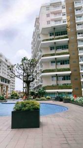 Daymentroom R32 Apartemen 2 BR Pasteur Bandung في باندونغ: عمارة سكنية كبيرة امامها شجرة