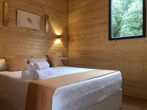 a bedroom with a bed in a wooden wall at Cabañas Compostela - Cabaña Sarela in Santiago de Compostela