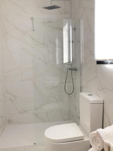 uma casa de banho branca com um chuveiro e um WC. em Cabañas Compostela - Cabaña Sarela em Santiago de Compostela