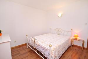 a bedroom with a white bed and a table at Apartments with a parking space Vrbnik, Krk - 429 in Vrbnik