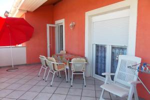 a patio with a table and chairs and a red wall at Apartments with a parking space Vrbnik, Krk - 429 in Vrbnik