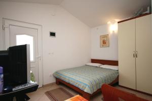 a small bedroom with a bed and a television at Apartments with parking space Vantacici, Krk - 427 in Malinska