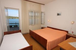 a bedroom with two beds and a view of the water at Apartments and rooms by the sea Luka, Dugi otok - 441 in Luka