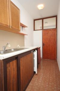 a kitchen with wooden cabinets and a sink and a door at Apartments by the sea Luka, Dugi otok - 441 in Luka